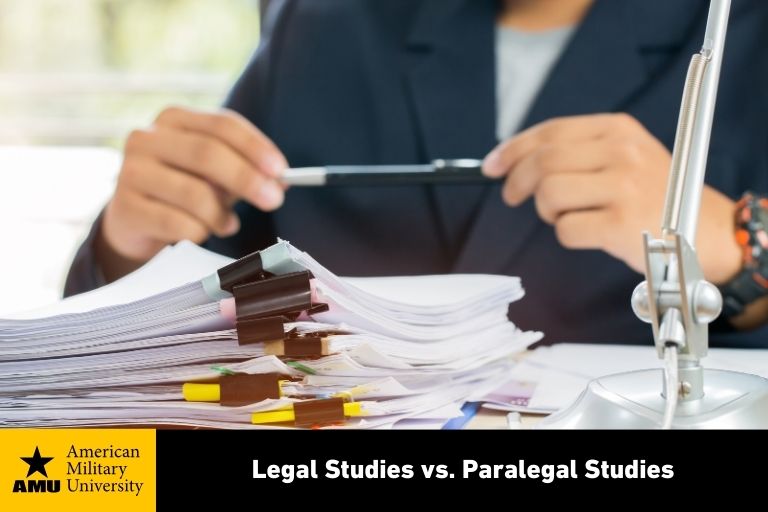 legal-studies-vs-paralegal-studies-amu legal studies professional at desk with stacks of contracts