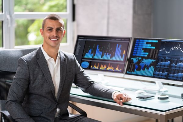 intelligence studies degree graduate sitting in front of large computer monitors